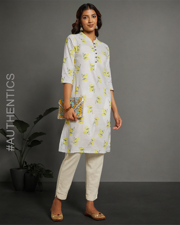 Stylish Sunny Yellow Floral Hand Block Cotton V-Neck Kurta, paired with off white pant and jutti, worn by a woman standing next to a flowerpot.