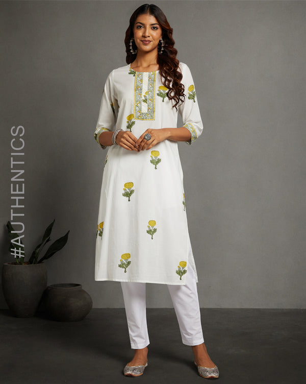 Stylish White Cotton Straight Kurta with Chinese Collar and V-Neck, paired with white pant and jutti, worn by a woman standing next to a flowerpot.

