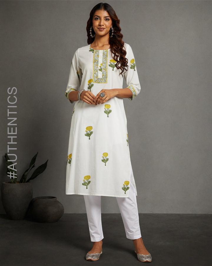 Stylish White Cotton Straight Kurta with Chinese Collar and V-Neck, paired with white pant and jutti, worn by a woman standing next to a flowerpot.

