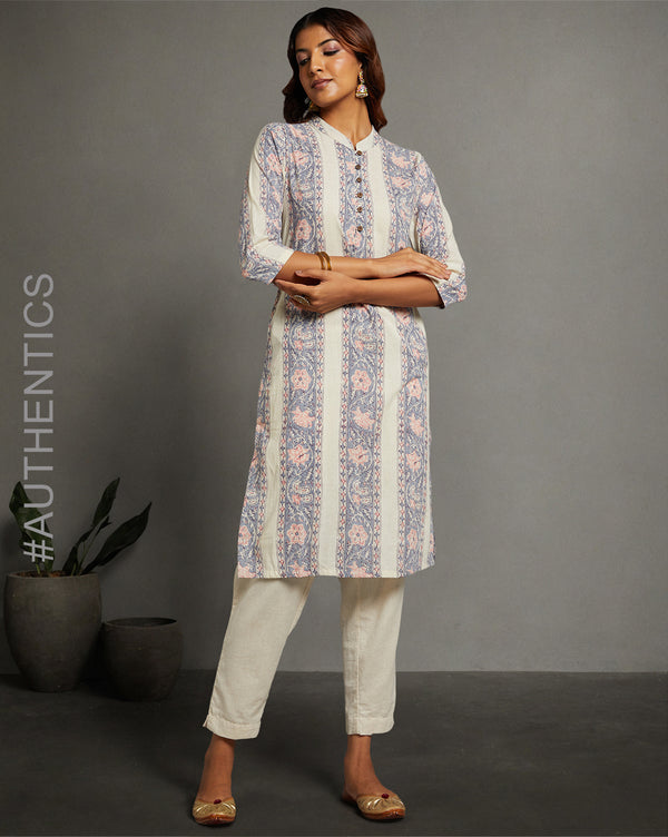 Stylish off white kurti with collar neck and wooden button design, paired with white pant and brown jutti, worn by a woman standing next to a flowerpot.