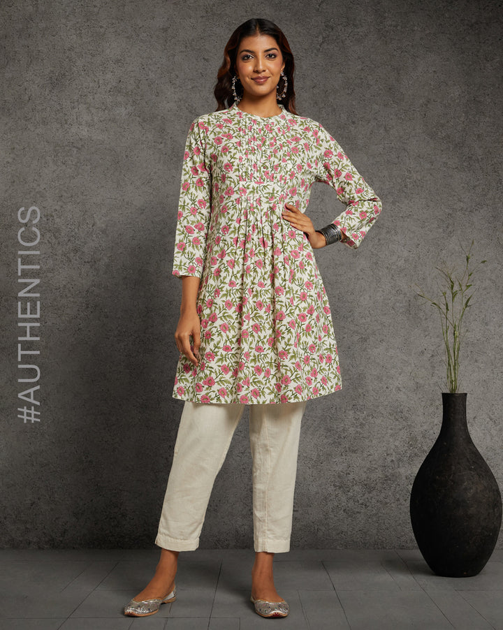 Stylish Floral Print Cotton A-Line Kurta, paired with off-white pant and jutti, worn by a woman standing next to a flowerpot.