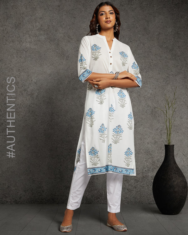 Stylish White Cotton Straight Kurta with Chinese Collar and V-Neck, paired with white pant and jutti, worn by a woman standing next to a flowerpot.
