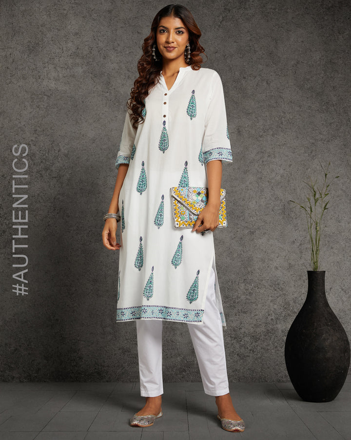 Stylish White Cotton Straight Kurta with Chinese Collar and V-Neck, paired with white pant and jutti, worn by a woman standing next to a flowerpot.

