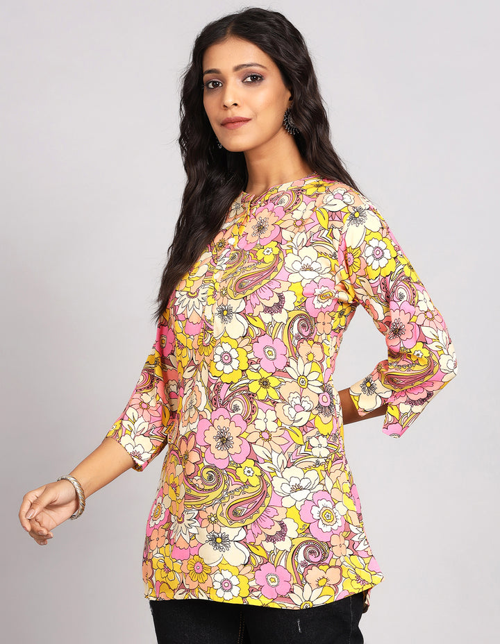 Side profile of a woman wearing a  Multi Color Short Kurti with Floral Print with three-quarter sleeve paired with black jeans and brown slippers,showcasing the kurti's length and the smooth drape over the body