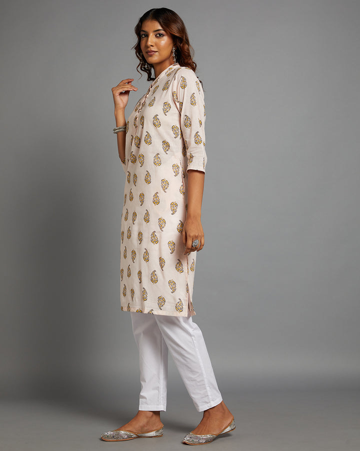 
Side profile of a woman wearing a Baby pink straight kurta  knee length and three-fourth sleeves paired with white pant and silver jutti, showcasing the kurti's length and the smooth drape over the body