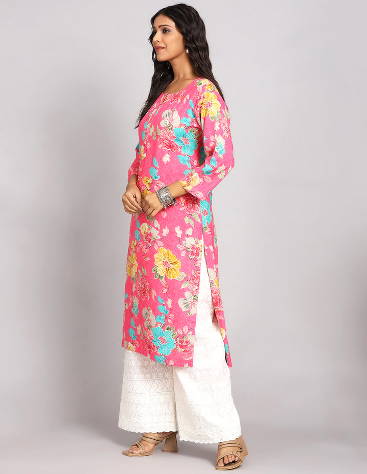 Side profile of a Pink Color Floral Print Long Kurti with Round Neck design and three fourth sleeves with white wide palazzo and brown sandals, showcasing the kurti's length and the smooth drape over the body