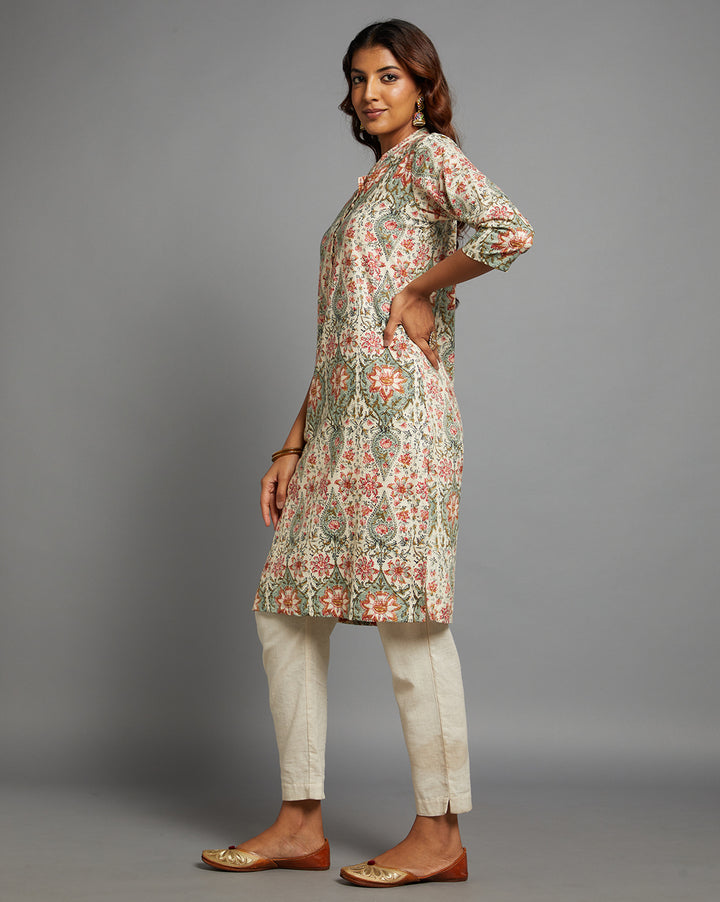 Side profile of a Yellow color floral print kurtii with three-quarter sleeve paired with white pant, showcasing the kurti's length and the smooth drape over the body