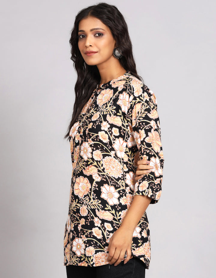 Side profile of a woman wearing a floral print black Kurti  with three-quarter sleeve paired with black jeans and brown slippers,showcasing the kurti's length and the smooth drape over the body