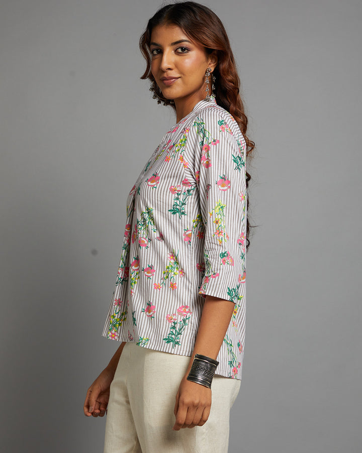 Side profile of a woman wearing Grey Floral print V neck Short Kurta with V-Neck with three-quarter sleeve paired with white pant and jutti, showcasing the kurti's length and the smooth drape over the body