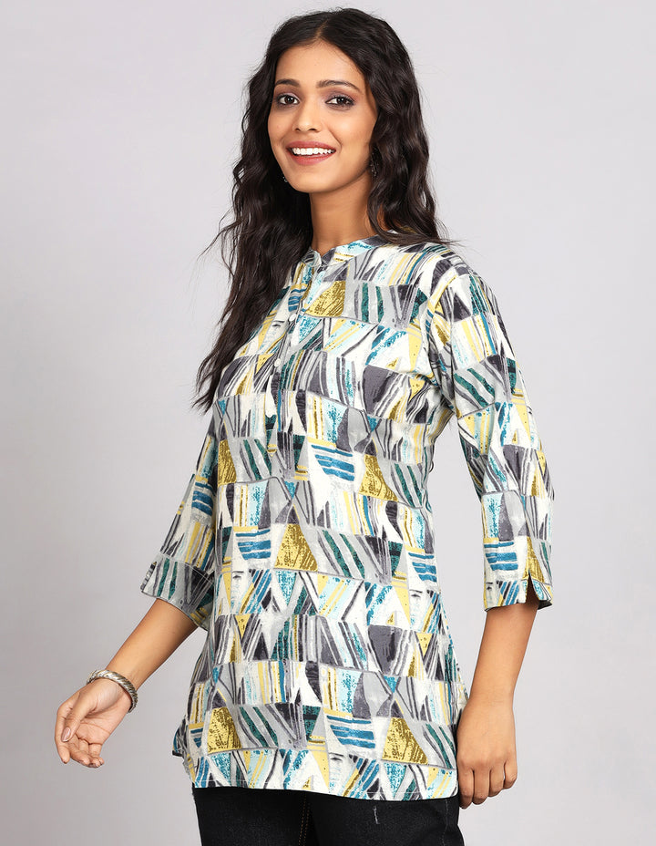 Side profile of a woman wearing a Printed Grey color Short Kurti  with three-quarter slitted sleeve paired with black jeans and brown slippers,showcasing the kurti's length and the smooth drape over the body