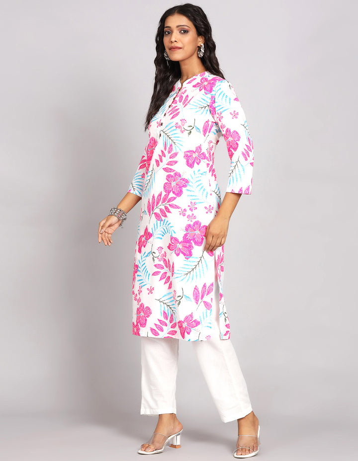 Side profile of a woman wearing a White Long Kurti With Floral print, paired with white payjama and white transparent sandals, showcasing the kurti's length and the smooth drape over the body