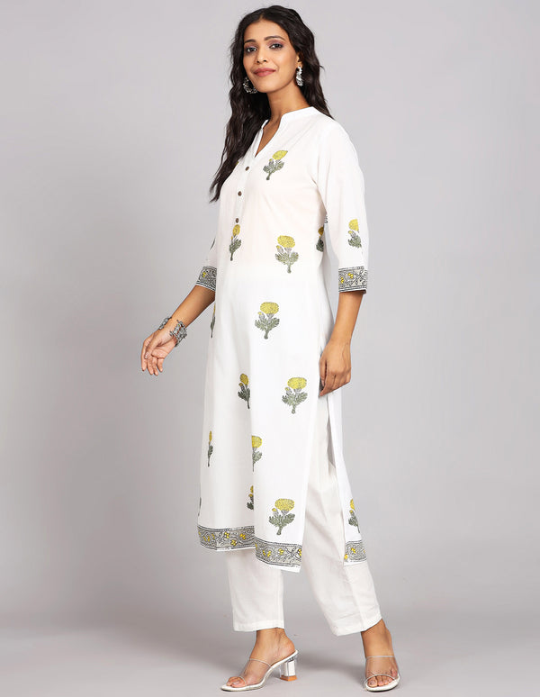 Stylish White Long Kurti With Floral print and Collar neck Design, paired with white payjama and white transparent sandals, worn by a woman standing on white floor.