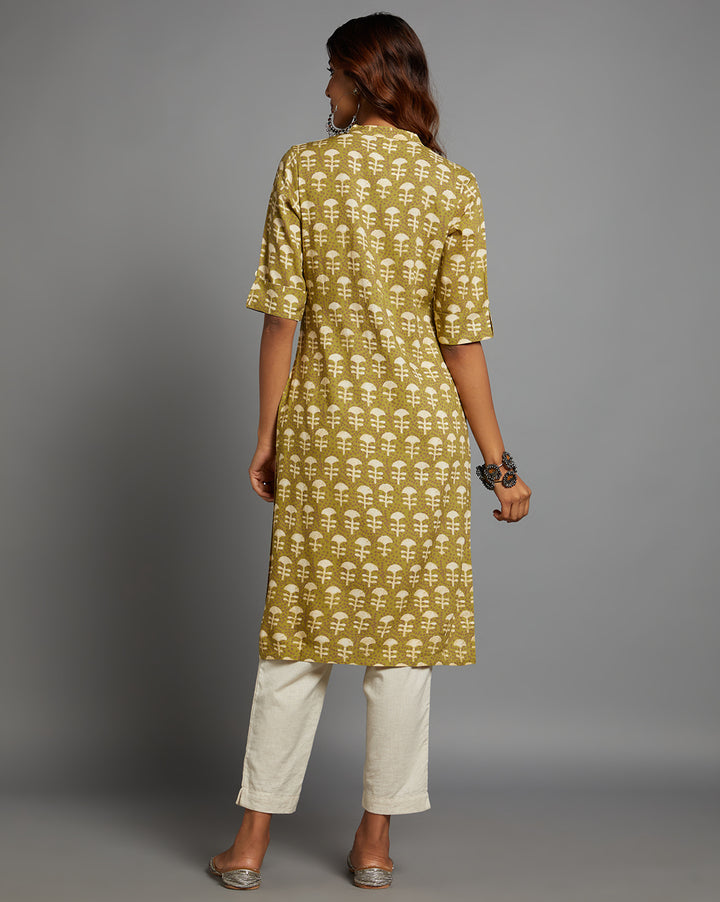 Woman showing the back view of a Printed green Cotton dabu print Kurti with three-fourth sleeves paired with white pant, highlighting the relaxed fit and simple design from behind.