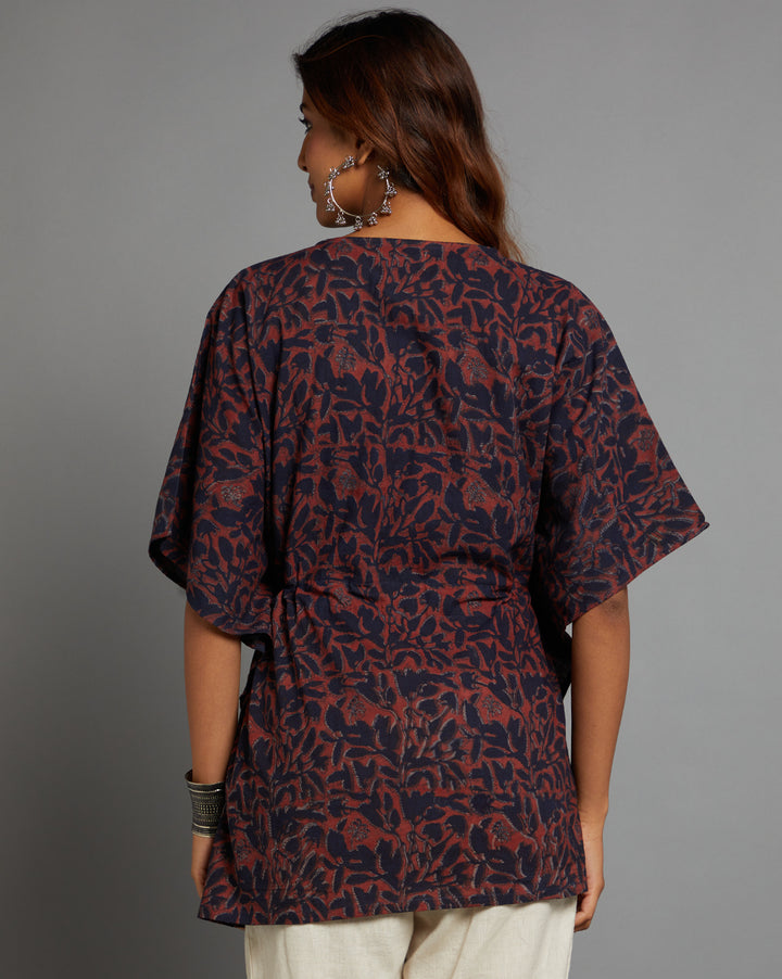 Woman showing the back view of a Dabu printed Navy and Maroon color cotton kaftan, paired with white pant and half sleeve , highlighting the relaxed fit and simple design from behind.
