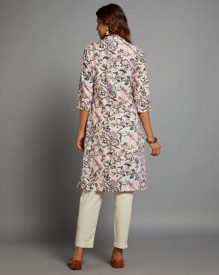 Woman showing the back view of a Pastel Yellow Floral Hand Block Cotton V-Neck Kurta, with three-quarter sleeve paired with white pant and jutti, highlighting the relaxed fit and simple design from behind.
