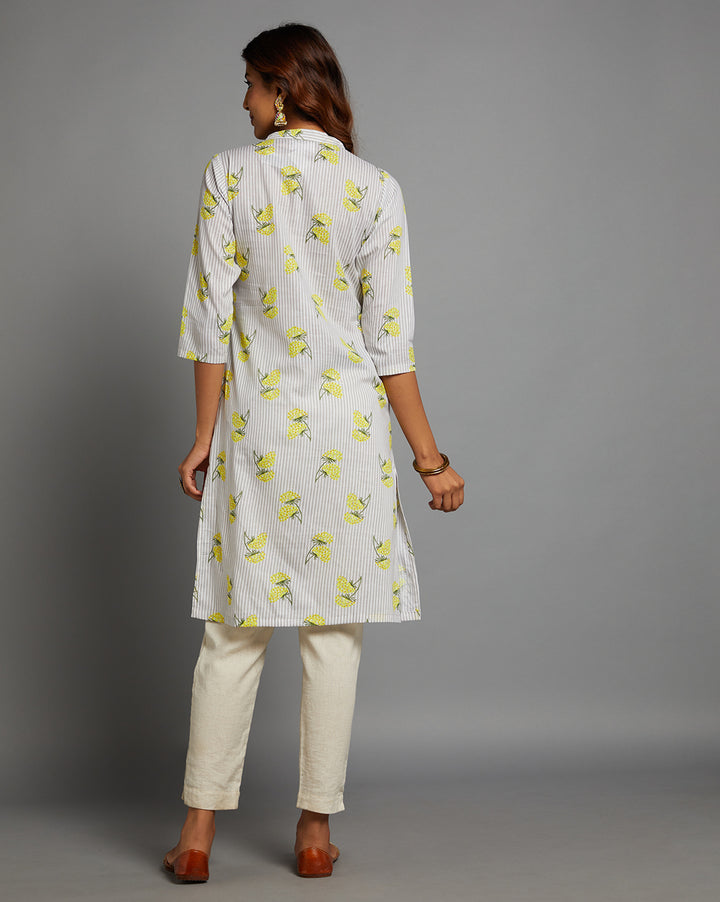 Woman showing the back view of a Sunny Yellow Floral Hand Block Cotton V-Neck Kurta with three-quarter sleeve paired with off white pant and jutti, highlighting the relaxed fit and simple design from behind.