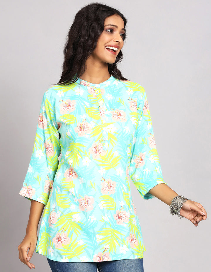 Side profile of a woman wearing a  Sky Blue Short Kurti wiht floral print with three-quarter sleeve paired with blue skinny jeans and brown sandals,showcasing the kurti's length and the smooth drape over the body