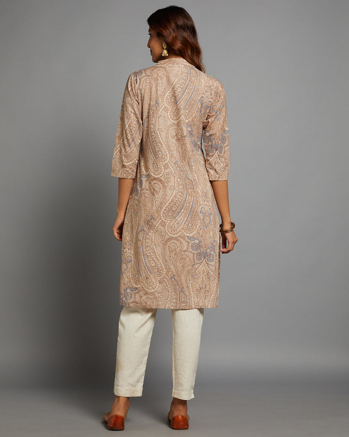 Woman showing the back view of a Brown Floral Hand Block Cotton V-Neck Kurti, with three-quarter sleeve paired with white pant and jutti, highlighting the relaxed fit and simple design from behind.
