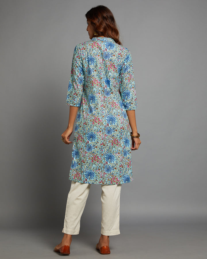 
Woman showing the back view of G Sky blue floral printed kurta knee length and three-fourth sleeves paired with white pant and golden jutti, highlighting the relaxed fit and simple design from behind.
