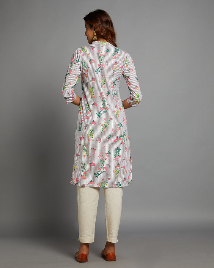 Woman showing the back view of a Grey Floral Hand Block Cotton V-Neck Kurta with three-quarter sleeve paired with off white pant and jutti, highlighting the relaxed fit and simple design from behind.

