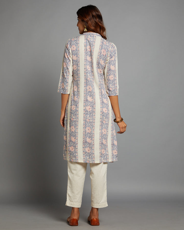 Woman showing the back view of a off white printed long kurti with three-quarter sleeve paired with white pant and brown jutti, highlighting the relaxed fit and simple design from behind.
