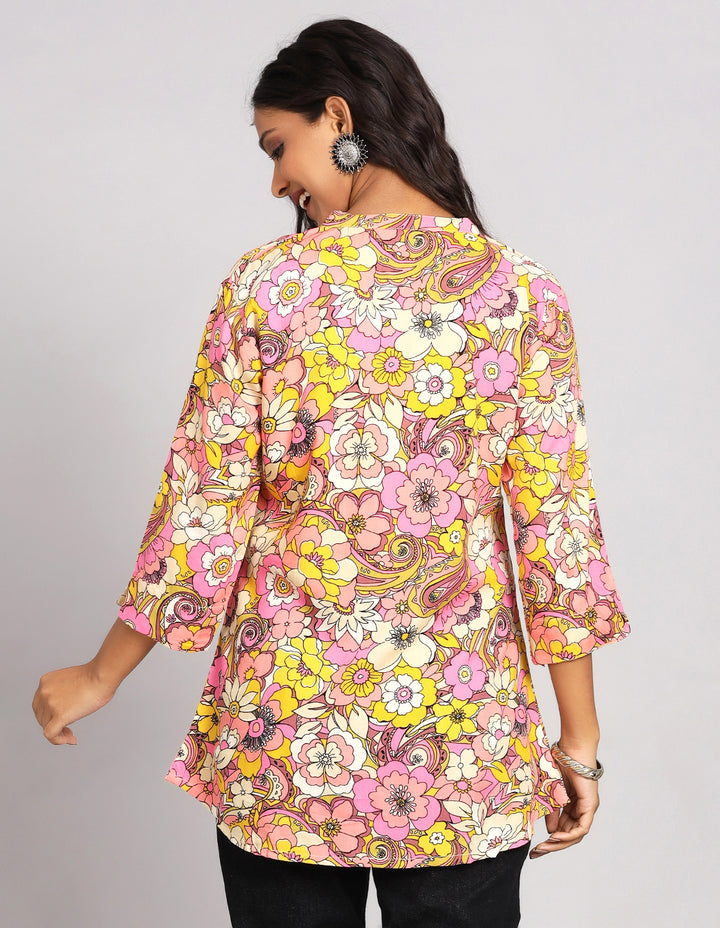 Woman showing the back view of Multi Color Short Kurti with Floral Print with slited three-quarter sleeve paired with black jeans and brown slipeers, highlighting the relaxed fit and simple design from behind.