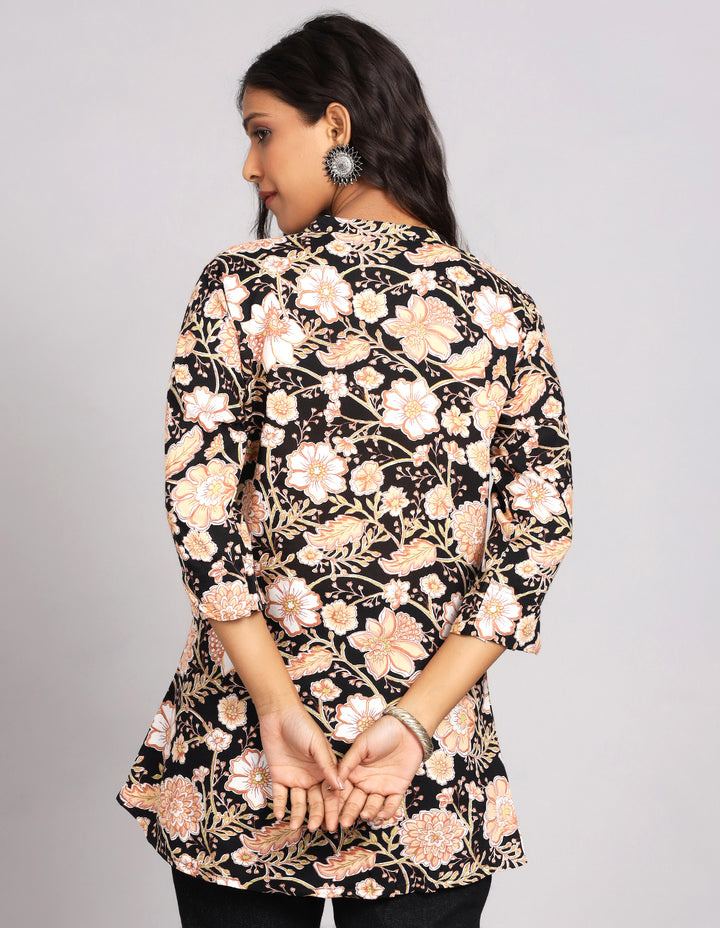 Woman showing the back view of a Printed black color Kurti with slited three-quarter sleeve paired with black jeans and brown slipeers, highlighting the relaxed fit and simple design from behind.