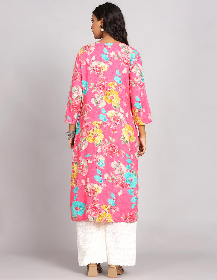 Woman showing the back view of a Pink Color Floral Print Long Kurti with Round Neck design with white wide palazzo and brown sandals, highlighting the relaxed fit and simple design from behind.
