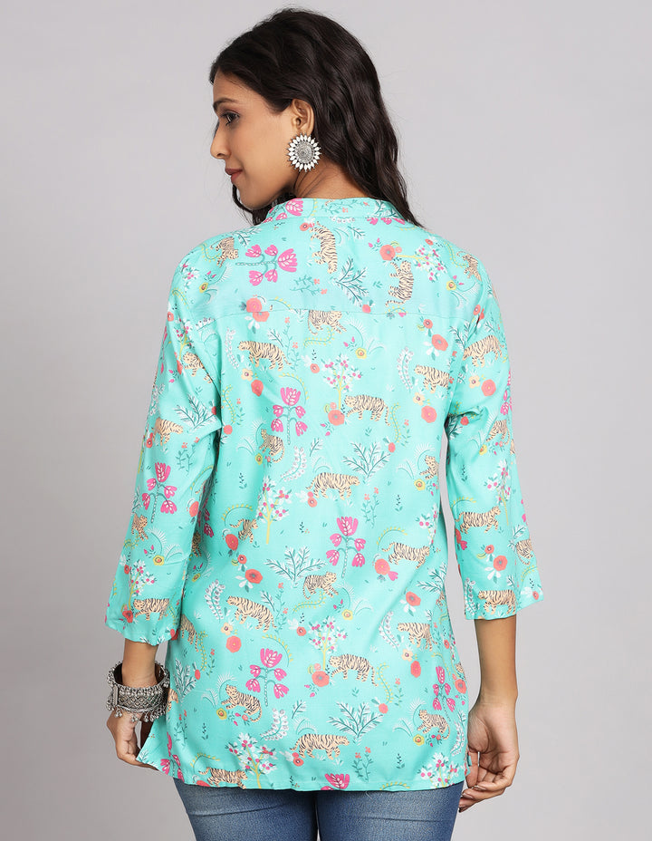 Woman showing the back view of Aqua Blue Floral Print Short Kurti with three-quarter sleeve paired with blue skinny jeans and brown sandals highlighting the relaxed fit and simple design from behind.