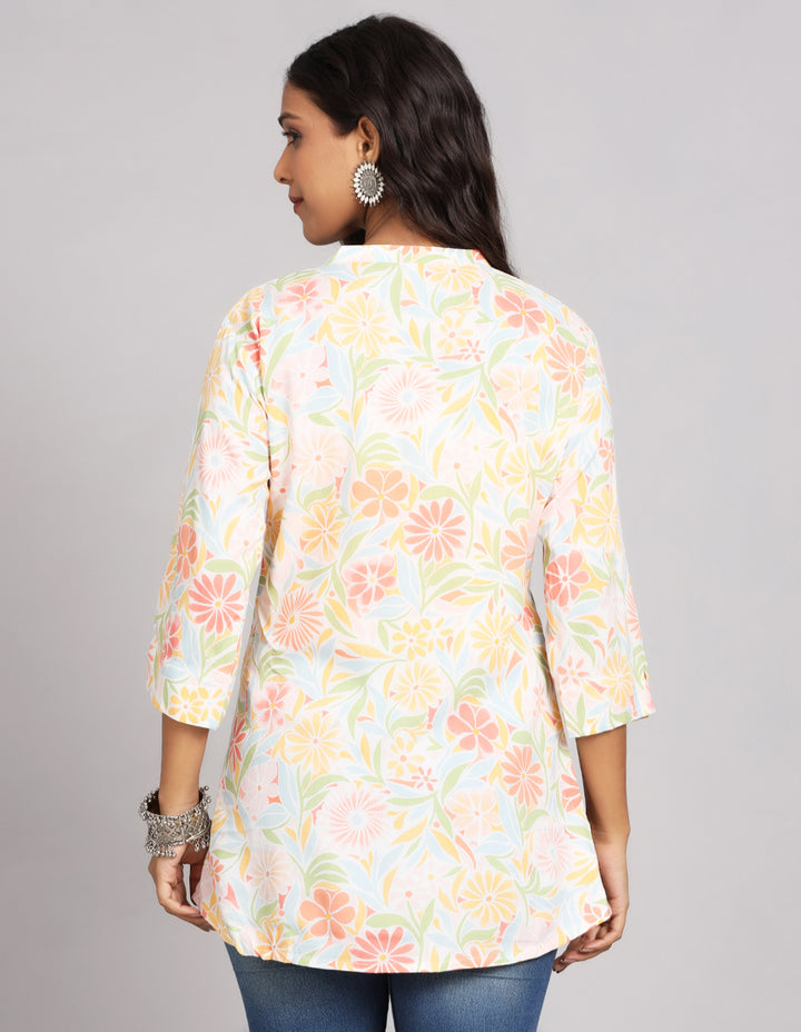 Woman showing the back view of a multicolor three-quarter sleeve short kurti paired with blue skinny jeans, highlighting the relaxed fit and simple design from behind.