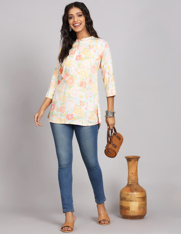 Stylish multicolor short kurti top with mandarin collar, paired with fitted blue jeans and brown heeled sandals, worn by a woman standing with brown bang in hand.