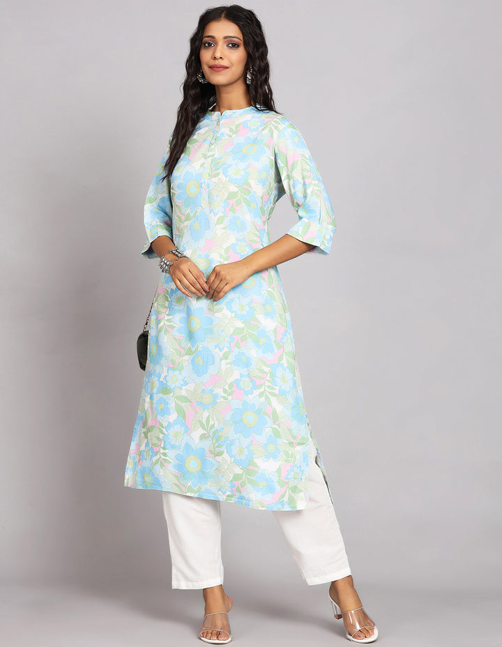 Stylish Sky Blue Long Kurti with Collar Neck Line with white pant and white transparent sandals, worn by a woman standing in white background.