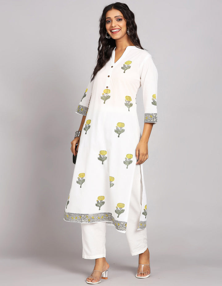 Side profile of a White Long Kurti With Floral print and Collar neck Design and three-quarter sleeve paired with white payjama and white transparent heals, showcasing the kurti's length and the smooth drape over the body