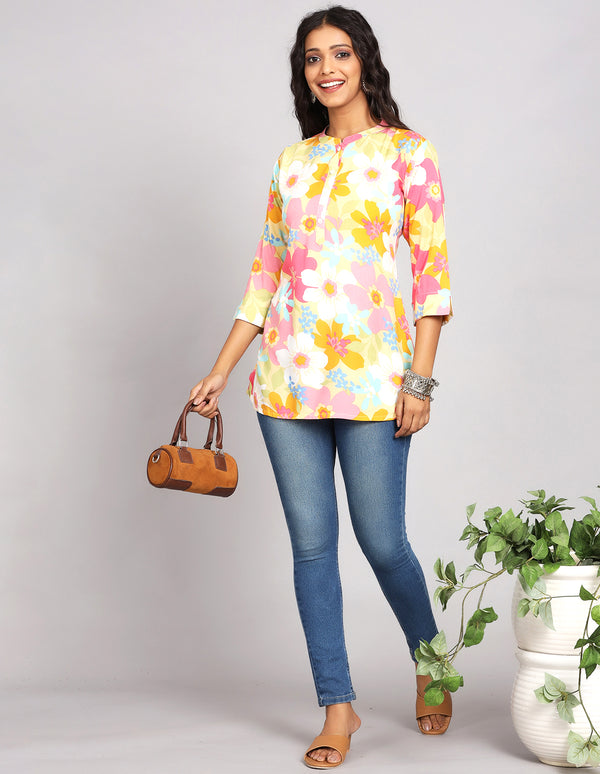 Stylish  Multicolor Short Kurti with Collar Neck Line, paired with Blue skinny jeans and brown sandals, worn by a woman standing next to flowerpot.