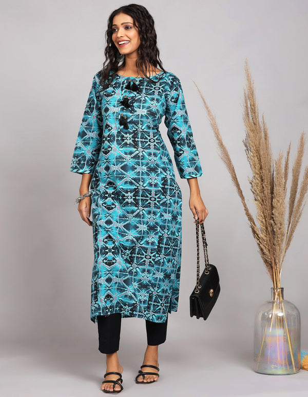 Stylish Printed Blue Cotton Kurti paired with black pant and black heels, worn by a woman standing next to a flower pot with open hair and taking white handbag.



